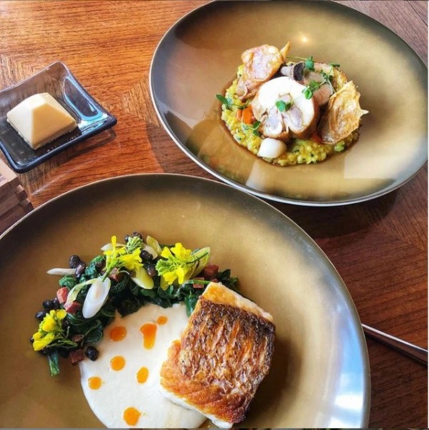 Food_In Front_Seared Bass, Onion Soubise, Spinach, Chorizo, Pickled Green Garlic and  Crispy Beans  In Back_ Vaduvan Chicken Roulade, Abborio Saffron Rice, Crispy Chicken Skin, Confit Leg, and Turnips.PNG