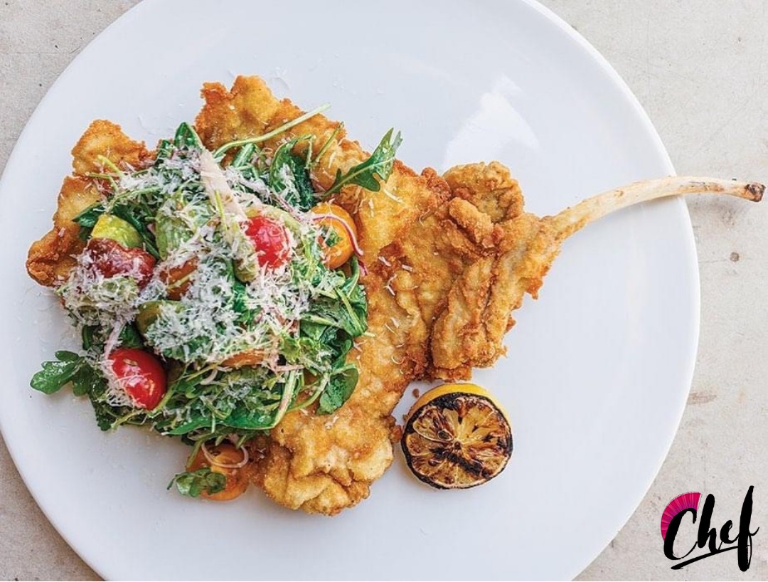 Pork Milanese Niman Ranch bone in pork chop, salad of arugula, cherry tomato, shallot, pecorino.  Charred lemon .PNG