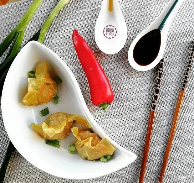 A woman enjoying a sushi dinner in a dim lighted room with a champagne glass next to her