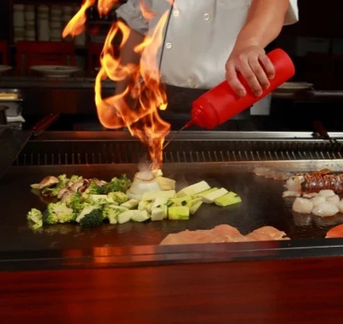 Kosher salt and seasoning sprinkled over beef on the grill