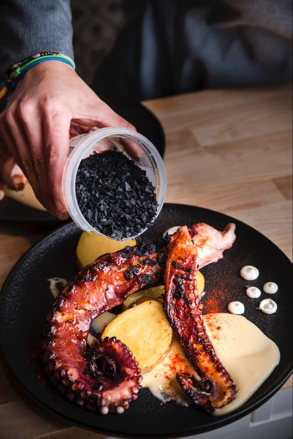 Hibachi grilled octopus tentacle served on a bed of green sauce with cherry tomatoes and shallots