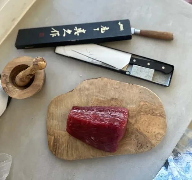 A smiling chef prepares ingredients on the kitchen counter on a white and well lit kitchen