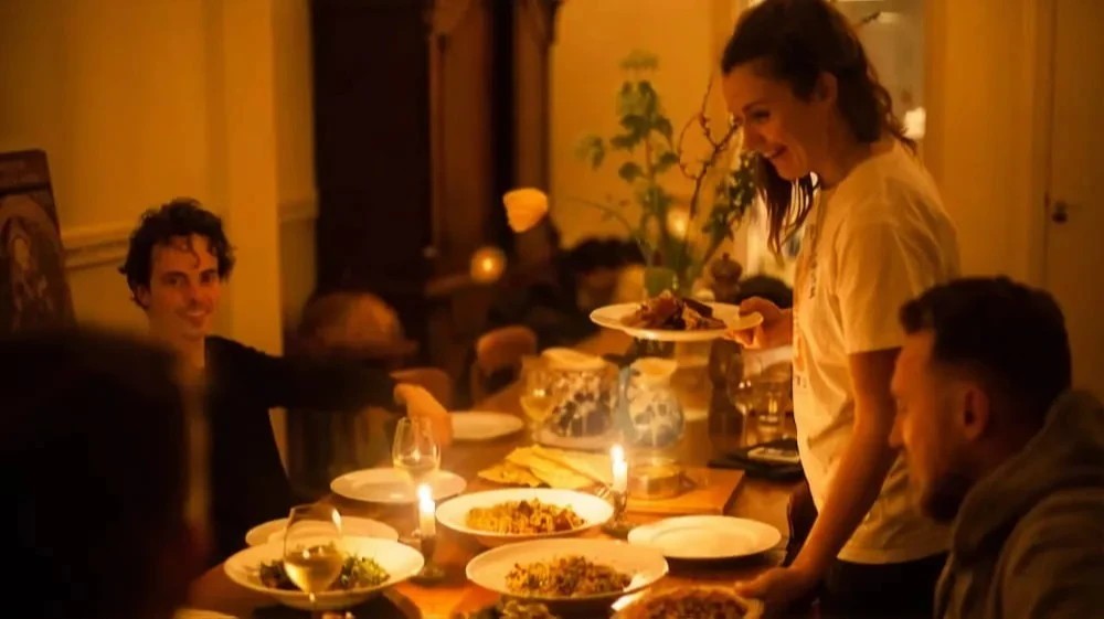 A candle lit dinner table with guests enjoying their meal while their chef finishes serving all the dishes