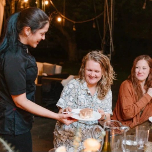 A chef serving a slice of tiramisu for one of her guests at the table