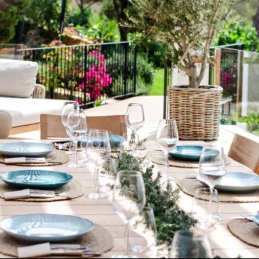 A lunch table served with glasses and plates outside on a sunny day