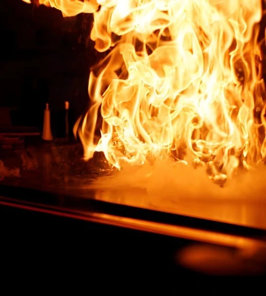 A flaming hibachi grill lighting up over a bed of steam